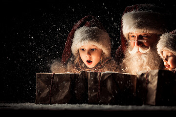 Joyful Children Surrounded by Santa Claus and Opened Giftboxes in Winter Wonderland Scene