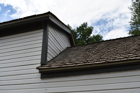 Two tiered roof. Standard asphalt shingles. Strait white wooden siding.