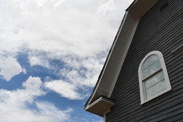 Barn window against fluffy clouded sky.