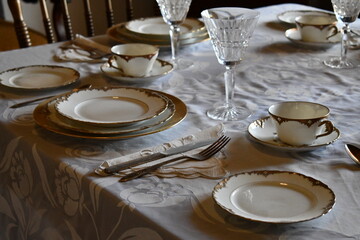Vintage dining set on square table. plates and accessories placed neatly for a formal dinner.