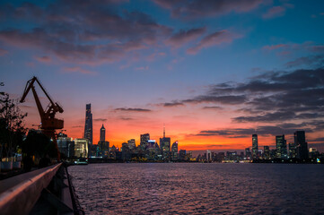 The urban skyline of the Huangpu River in Shanghai, China, under a beautiful sunset.