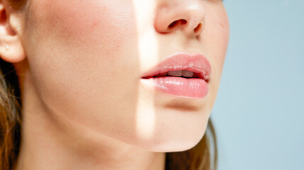 Obraz premium A close-up beauty photograph of a young woman's face showing a perfect, glossy pink lips and flawless skin