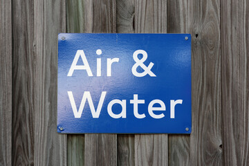 Blue Air And Water sign attached to a wooden fence