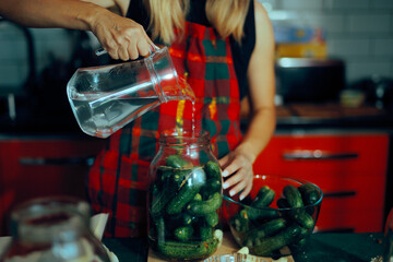 Housewife Pours Salt Water into Jars of Cucumbers for Pickling. Woman prepares pickles using a family recipe at home 
