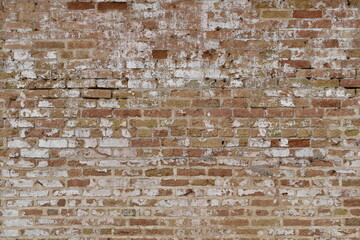 Very old red brick wall. Faded, cracked and crumbling with time.