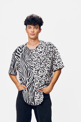 Young man wearing a black and white animal print shirt stands confidently with hands in pockets...