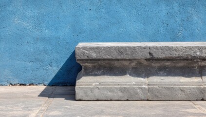 Gray stone bench against a vibrant blue wall