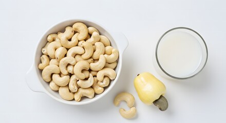 A bowl of cashew nuts next to a cashew fruit and a glass of cashew juice isolated on white background