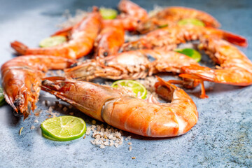Cooked prawns with lime and rosemary on blue background