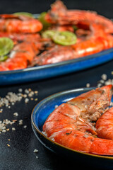 Grilled prawns with lime and rosemary resting on blue plates with salt