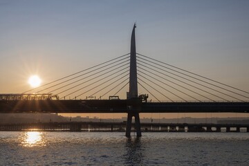 Scenic sunset view of the Golden Horn Metro Bridge in Istanbul with warm sunlight, a passing boat,...