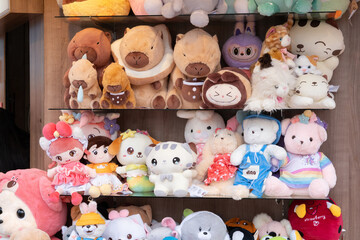 A collection of dolls of various sizes and characters displayed on open shelves at a carnival.