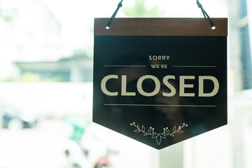 A glass door with CLOSED store sign, tag at cafe or restaurant hang on entrance door.