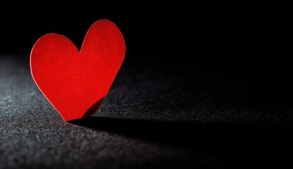 Red paper heart on dark surface, dramatic light, Valentine's Day card design