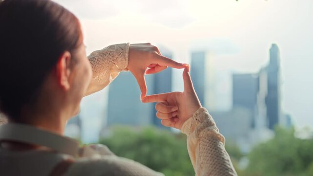 Closeup - Hands of Asian woman raises her hands and make the finger frame with the background of the city, Travel, Business planning new year.