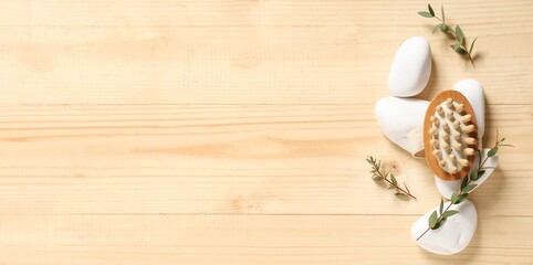 Massage brush, spa stones and eucalyptus branches on wooden background with space for text
