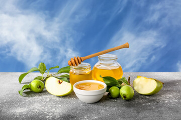 Jars with sweet honey and green apples on table against white background