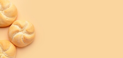 Delicious kaiser rolls on beige background with space for text