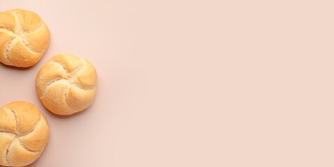 Delicious kaiser rolls on beige background with space for text