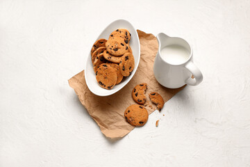 Bowl of cookies and jug with milk on white background