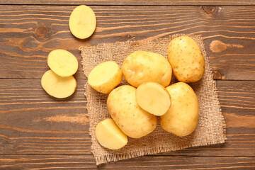 Raw baby potatoes and slices on wooden background