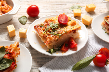Plates of pasta with tomato sauce and cheese on white wooden background