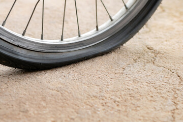 An old bike that has back flat tire parked by the urban road in the evening of the day and waited...