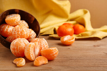 Bowl with scattered peeled tangerines on wooden table