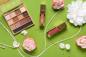 Eyeshadows palette with lip glosses, accessories and roses on green background