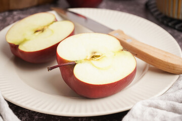 Plate with halves of fresh red apple on dark table