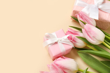 Pink tulips with gift boxes on beige background