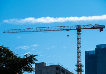 Construction cranes are silhouetted against a bright blue sky, signifying urban development and growth.