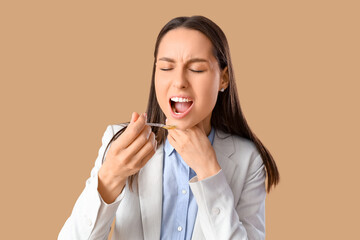 Young woman with syrup for sore throat on brown background