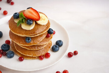 Plate with tasty pancakes and berries on white table