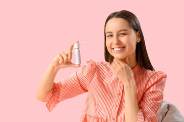 Young woman with spray for sore throat on pink background