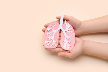 Female hands with paper lungs on beige background