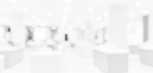 Blurred white interior space with display tables and a central pillar, softly lit to create an airy, minimal, and contemporary exhibition-like atmosphere.