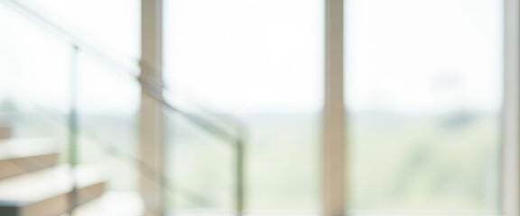 Fototapeta premium Blurred interior view with a staircase and large window revealing lush greenery outside, creating a tranquil and airy atmosphere that feels open and naturally bright.