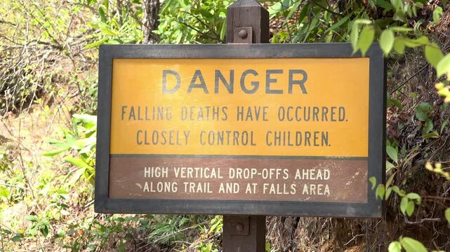 Warning for dangerous vertical drop-offs near cliffs on forest trail