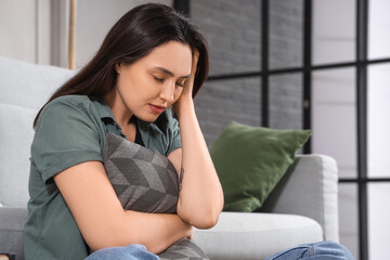 Depressed young woman with pillow at home