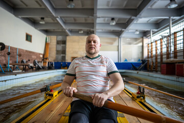 Dedicated powerful athletic rowers in perfect synchronization stroking puddling on indoor rowing simulator. Team coordination, power endurance body building, competitive preparation for challenges