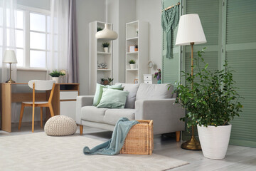Interior of living room with green folding screen, sofa and plants