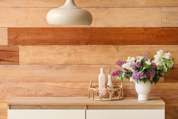 Vase with flowers on wooden cabinet in room