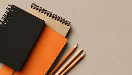 Three notebooks, various colors, and pencils on a neutral background