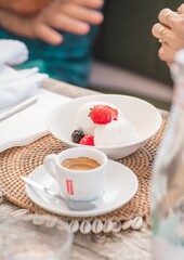 close up ice cream and red fruits dessert with a coffee on a restaurant table