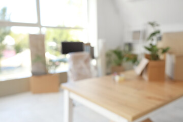 Blurred view of desks with cardboard boxes in office on moving day
