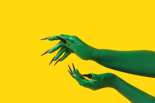 Green hands of witch on yellow background. Halloween celebration