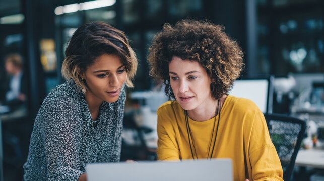 Collaboration in the Digital Realm: Two professionals, engrossed in a focused discussion, explore a digital interface with a mix of technological tools