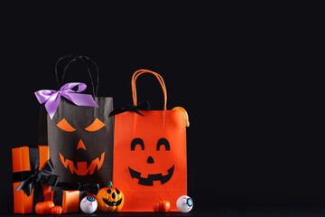 Halloween shopping bags with gift boxes and candies on black background