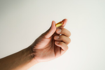 Male hand holding Fish oil capsules with omega 3, omega 9, vitamin D, vitamin E, Cod liver oil